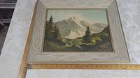 Full view of 17 x 20 inch framed oil painting depicting Canadian Rockies mountains with trees and valley, mounted on masonite.