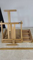 Front view of portable art easel showing adjustable stand and drawer open to the side with compartments.