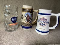 Three vintage beer mugs arranged in a row on a gray surface.