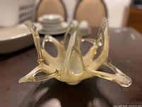 Close-up photo showing the translucent amber-colored handblown art glass candy dish with multiple elongated petal-like protrusions.