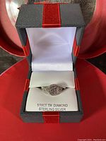 Front angle view of the sterling silver diamond cluster ring inside the gift box, showing the ring and box interior.