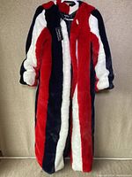 Full view of the long fur coat with red, white, and navy blue vertical stripes, showing length and texture.
