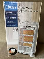 Front view of the Midea heater in its original box showing the product image, brand, and feature highlights such as ultra quiet operation, 3 heat settings, adjustable thermostat, tip over and overheat protection.