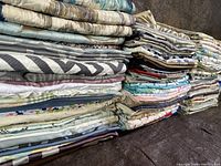 Stacks of folded pillow cases in a variety of colors and patterns, showing volume and fabric types.