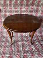 Front view of a wooden oval vintage side table with drop leaf design and dark brown finish.