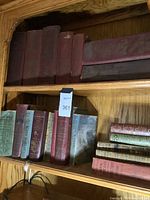 Seven red clothbound city directories and one horizontal directory on upper shelf