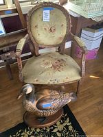 Front view of upholstered armchair and carved duck sculpture together