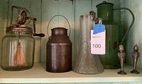 Antique churn, metal milk can, glass pitcher, green metal jug, salt and pepper shakers shown together