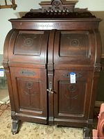 Front view of closed desk showing double roll-top doors and carved floral panels