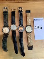 Four wristwatches face up on wooden surface