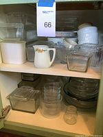Two shelves of kitchenware displaying clear glass storage containers with lids, white milk glass container, ceramic and glass pitchers, ramekins and CorningWare dishes