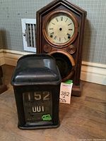 Overall view of black metal indicator and wooden mantel clock