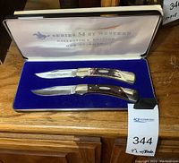 Two knives in blue velvet presentation case with white lid