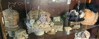 Display cabinet with several Victorian hats and vanity decor items including jewelry boxes and brushes.
