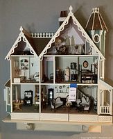 Front elevation showing entire two-story dollhouse with attic and turret, interior rooms visible