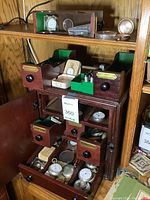 Full view of wooden cabinet with drawers open showing pocket watches and parts