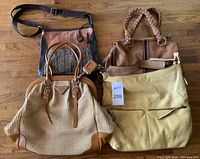 Group shot of four handbags on wooden floor showing overall condition and style variety