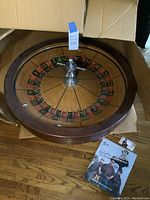Overview of roulette wheel with signed photo and card on wooden floor
