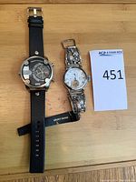 Overview of both watches on wood surface with lot number card