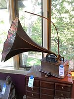 Full view of phonograph on cabinet showing painted floral horn and oak case