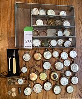 Full lot overview showing watches, parts, tools and coins laid out