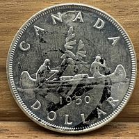 Reverse side of the 1950 Canadian silver dollar showing the canoe scene with paddlers and the year 1950, with visible surface marks including a black mark.