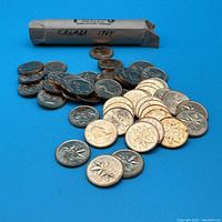 Photo of a roll labeled 'Canada 1964' with numerous copper Canadian pennies scattered in front, showing the maple leaf reverse side.