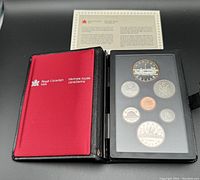Photo showing the opened black presentation book with the 1984 Canadian coin set and certificate inside.