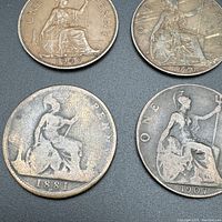 Four British large pennies dated 1947, 1920, 1881, 1907 showing Britannia seated design and inscriptions.