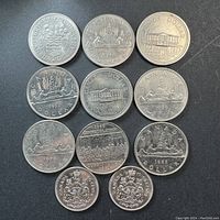 Photo showing all 11 coins, 9 Canadian nickel one dollar coins with various commemorative and standard designs, and 2 half dollar coins with the Canadian Coat of Arms.