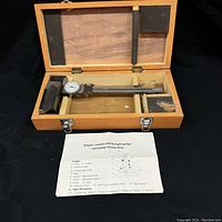 Open wooden box containing the dial height gauge, accessories, and instruction sheet.