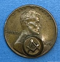 Obverse of 1964 Lincoln penny with a clear masonic square and compass symbol stamped on the lower front area around the date '64'.
