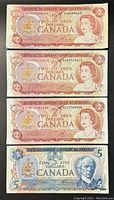Front side of three Canadian $2 notes and one Canadian $5 note showing portraits and denominations.