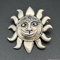 Front view of sterling silver sunshine face brooch showing detailed smiling face and sun rays.