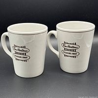 Two white ceramic mugs with black Tim Hortons logos, shown front view