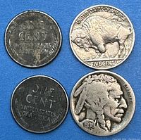Four American coins including two steel cents and two Buffalo nickels laid out on a blue background; obverse and reverse shown.