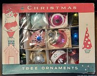 Original box containing 12 assorted vintage glass Christmas tree ornaments in separate compartments, visible paint wear and some damage.