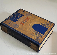 Book lying closed showing front cover design with blue and gold Assyrian arch and mythical figures.