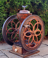 Front view of grinder showing body, wheels, wooden grounds drawer