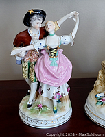 Side view of porcelain figural group showing man and woman dancing with detailed period clothing.
