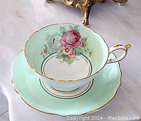 Side view of cup resting on saucer showing floral design and gold trim