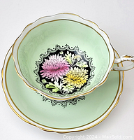 Top view image of cup placed inside matching saucer showing floral design and gold trim on both pieces.
