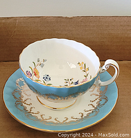 Porcelain cup placed inside saucer showing blue and gold pattern with floral interior design.