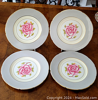 Four Coalport dinner plates with pink rose design and gold trim arranged on a table, showing overall set condition and design.