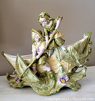 Wide front view of porcelain figural group showing two children, boat, and water base with floral and duck details.