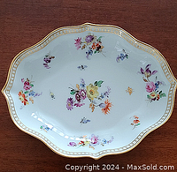 Top view of porcelain bowl showing multi-colored floral designs and gold trim around rim.