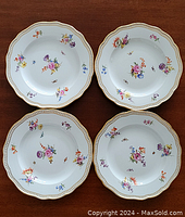 Four Meissen plates arranged on wood surface