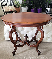 Front view of oval wooden parlor table showing smooth oval top and ornate wooden base