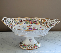 Front view of Dresden porcelain footed compote showing floral decoration and reticulated handle edges with gold trim.