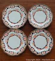 Four porcelain octagonal plates with Imari pattern arranged on a wooden surface.